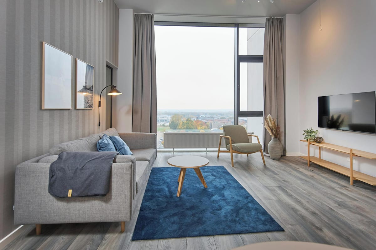 Una sala de estar moderna con un sofá, un sillón y un televisor.
