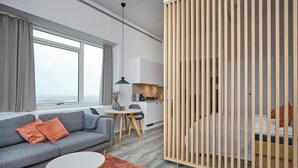 Ein modernes Zimmer mit einer Couch, einem kleinen Tisch, einem Bett und einer Küchenzeile.
