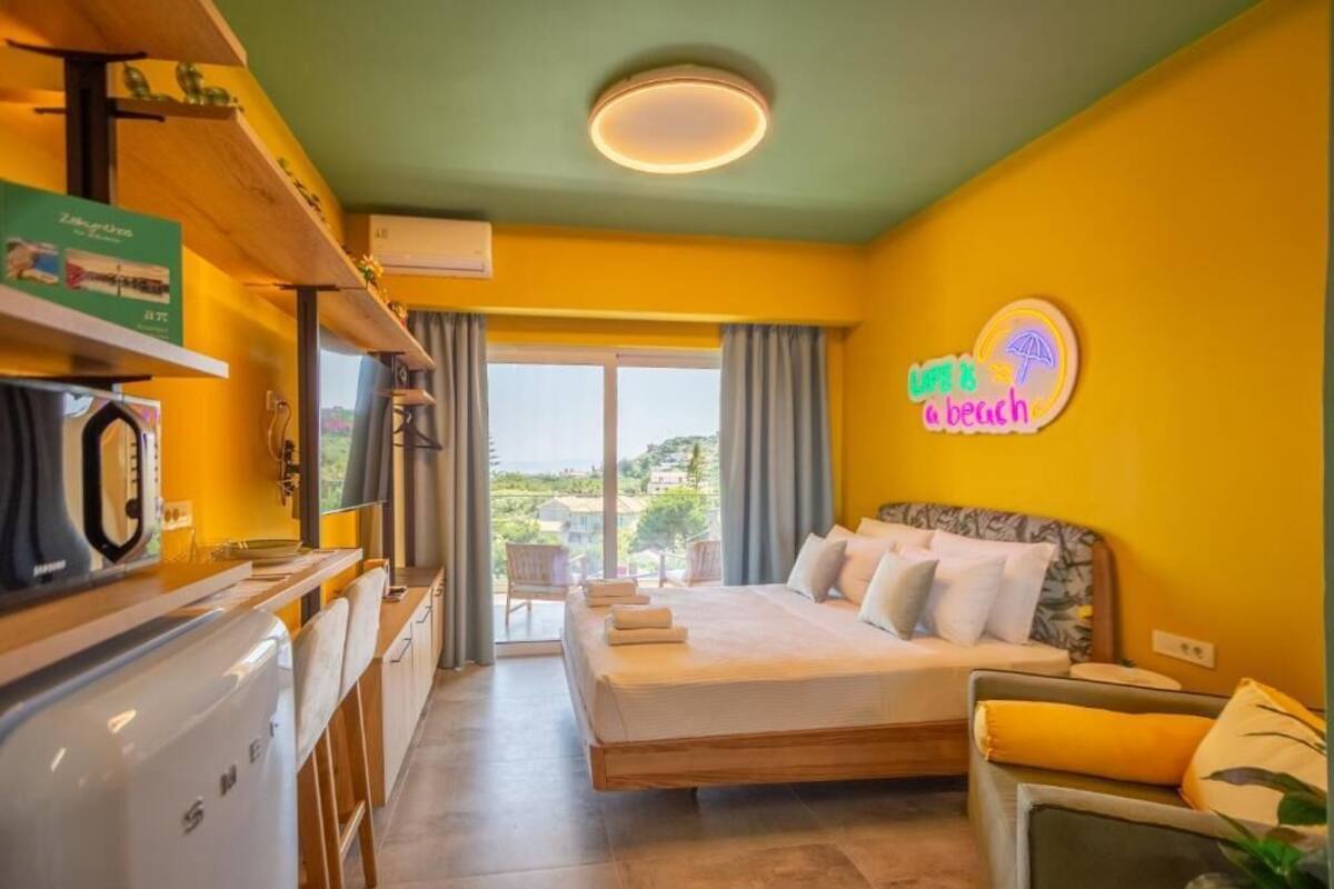 A hotel room with a bed, a desk, a microwave, a sink, and a view of the outdoors.