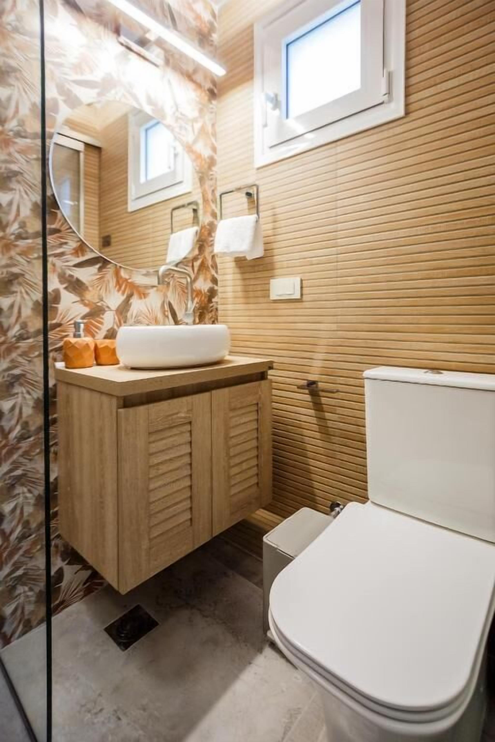 Un baño con tocador de madera, inodoro blanco y espejo.