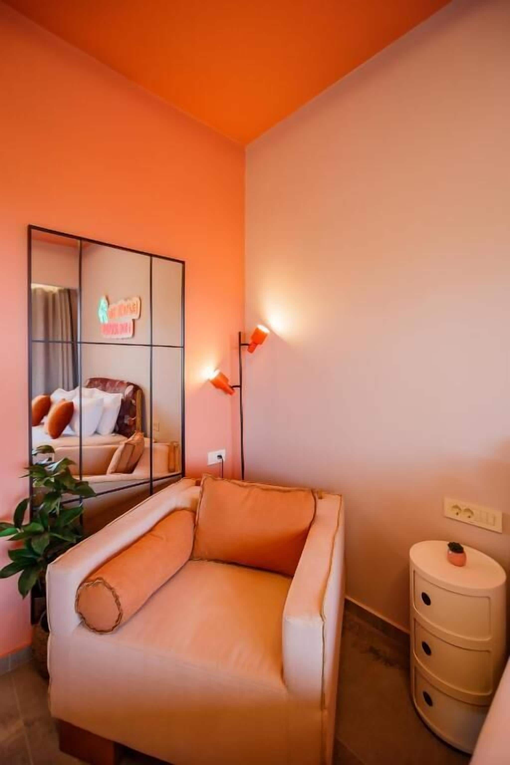 Ein Zimmer mit einer Couch, einem Nachttisch, einem Spiegel und einer Wandleuchte.