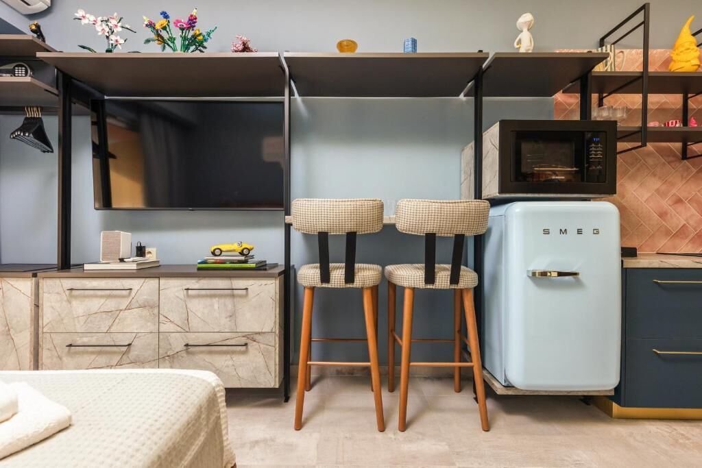 A compact kitchen with two stools, a microwave, and a refrigerator.