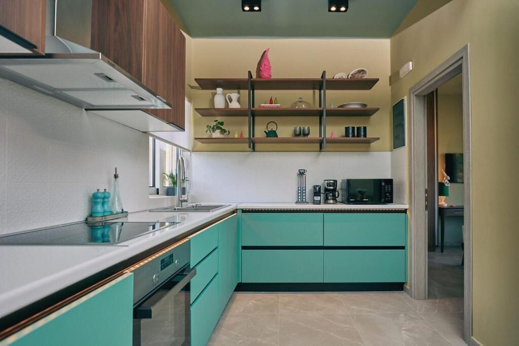 Een moderne keuken met blauwgroene kastjes, een roestvrijstalen afzuigkap en een koffiezetapparaat op het aanrecht.