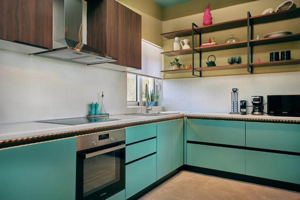 Een moderne keuken met blauwgroene kastjes, een inbouwoven, een magnetron en een koffiezetapparaat.