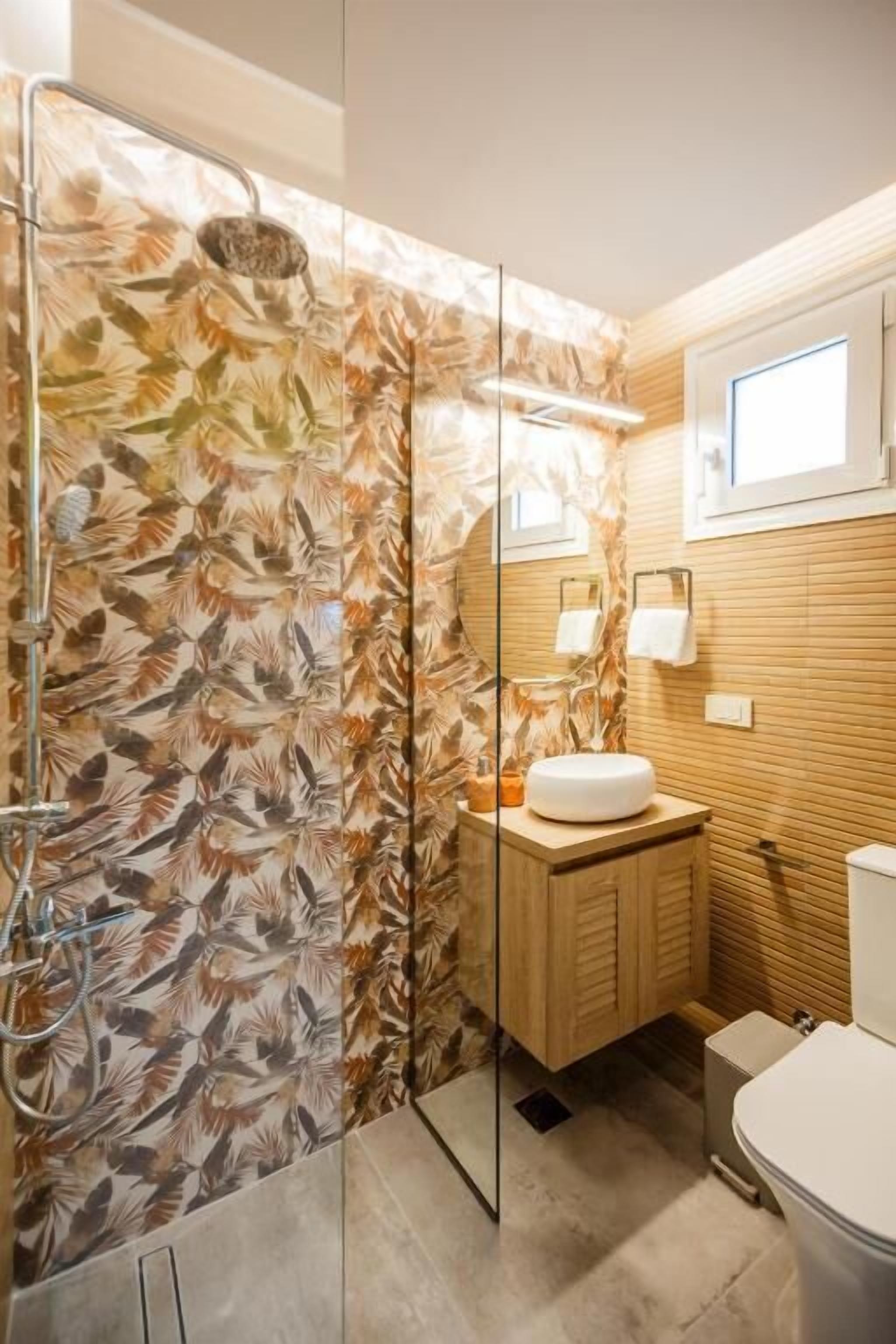 Een badkamer met douche, toilet en wastafel, met een houten wastafelmeubel en een spiegel.