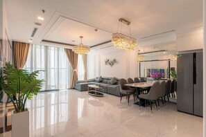 Una sala moderna con un sofá modular, una mesa de comedor y sillas, un ventanal con cortinas y un refrigerador.