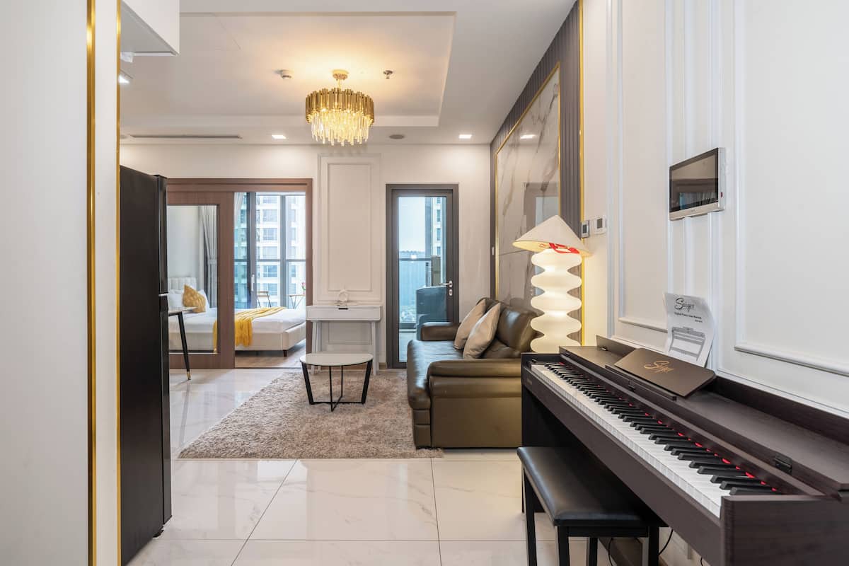 A modern living room with a piano, a sofa, a coffee table, and a chandelier.