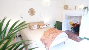A bedroom with a bed, a fireplace, and a hanging light fixture.