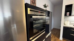 Eine Küche mit Einbauofen, Kühlschrank und Holzboden.