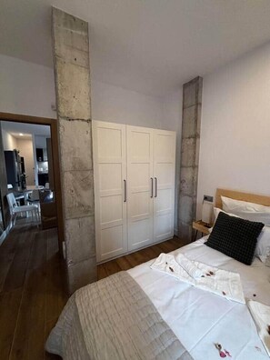 A bedroom with a bed, a wardrobe, a nightstand, and a mirror.