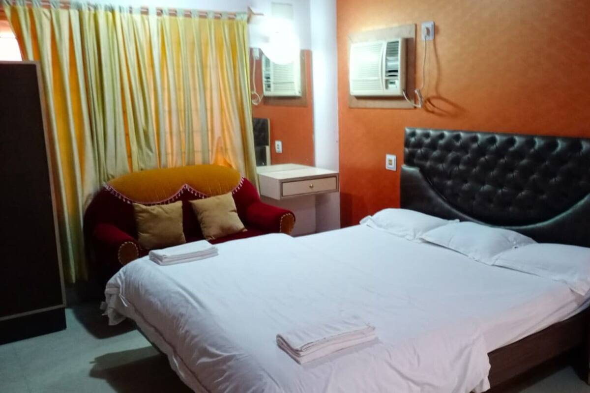 Una habitación de hotel con cama, escritorio, silla y aire acondicionado.