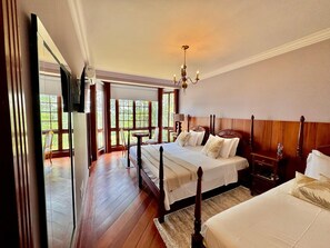 Un dormitorio con dos camas, una araña, un televisor y vistas al exterior.