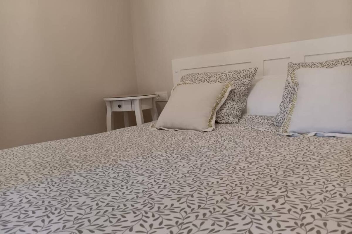 Une chambre à coucher avec une couvre-lit à motifs, une table de chevet et deux oreillers.