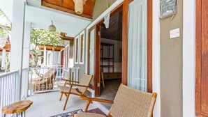 Uma área externa coberta com cadeiras de vime, um tapete estampado e uma mesa de madeira.
