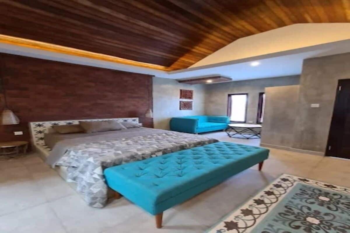 A bedroom with a bed, a bench, a sofa, and a patterned rug.