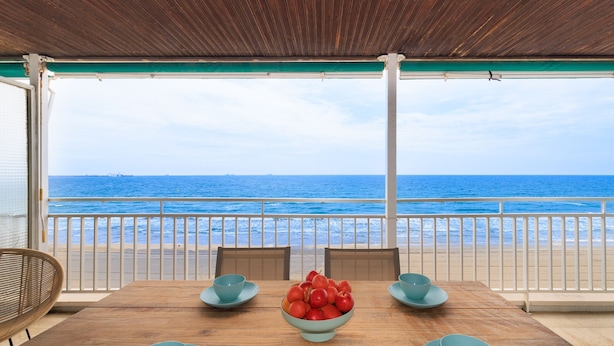 A wooden table with a bowl of red apples, two blue bowls, and a wicker chair. - Beachfront | Spectacular sea views (La Pineda)