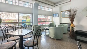 A spacious room with a dining area, seating, a flat-screen TV, and large windows. - Hotel Santiago (Rimini)