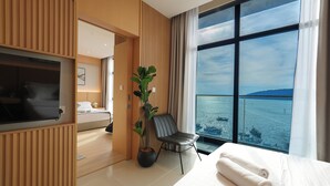 A hotel room with a bed, a TV, a plant, and a view of the sea. - The Voyagers Home Borneo Kota Kinabalu (Kota Kinabalu)