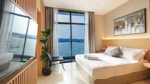 A modern hotel room with a large bed, a potted plant, a view of the sea, and a painting on the wall. - The Voyagers Home Borneo Kota Kinabalu (Kota Kinabalu)