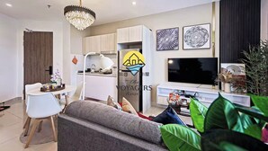 A modern living room with a sofa, a dining table, a kitchen area, and a TV. - The Voyagers Home Borneo Kota Kinabalu (Kota Kinabalu)