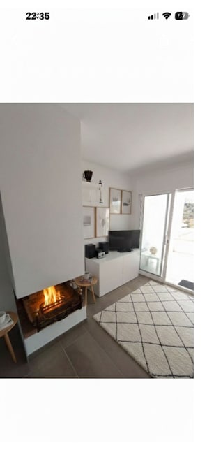 Ein modernes Wohnzimmer mit Kamin, einer Küchenzeile und einer großen Glasschiebetür zum Außenbereich.