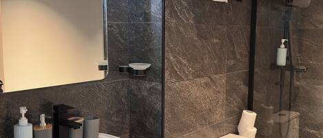 Une salle de bain moderne avec un grand lavabo blanc, une douche à parois de verre et un porte-serviettes.