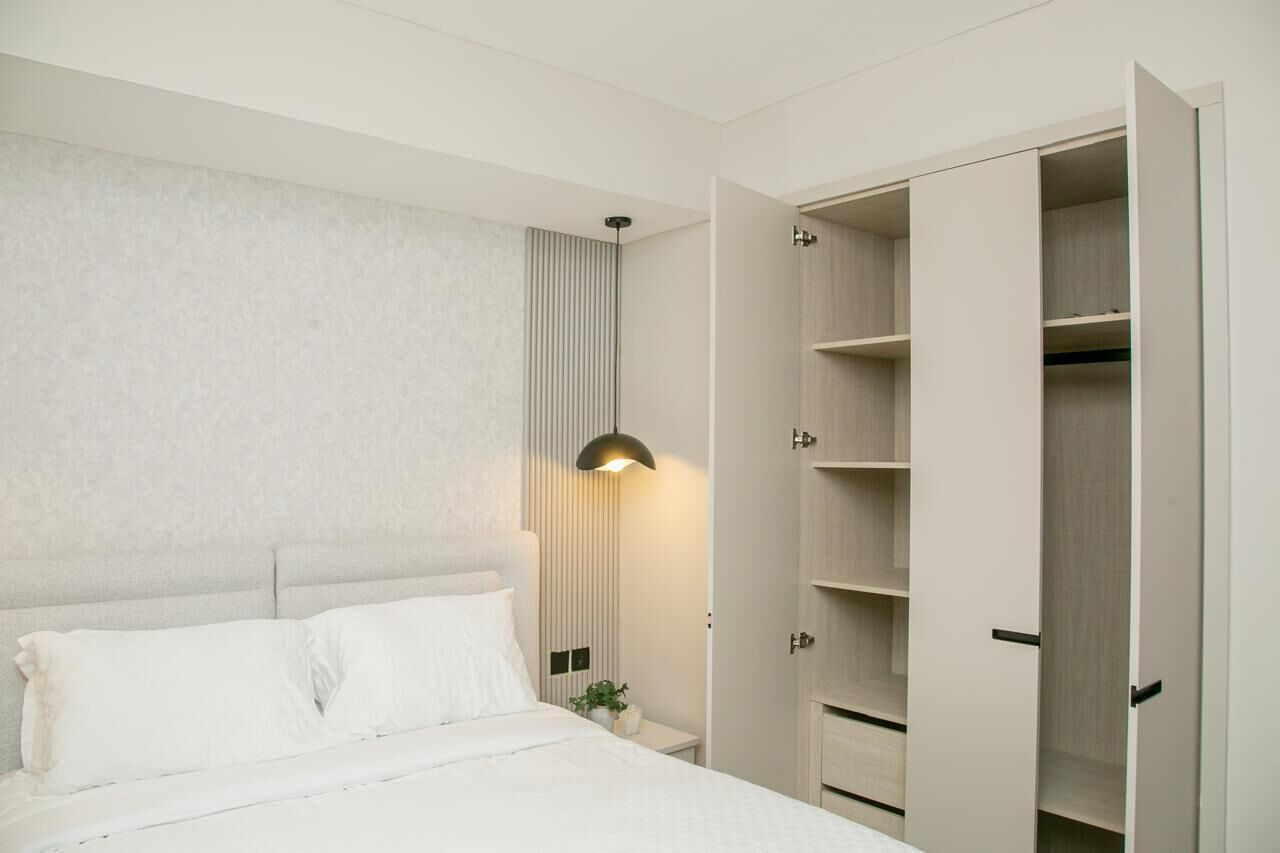 A bedroom with a bed, bedside table, lamp, and open wardrobe.