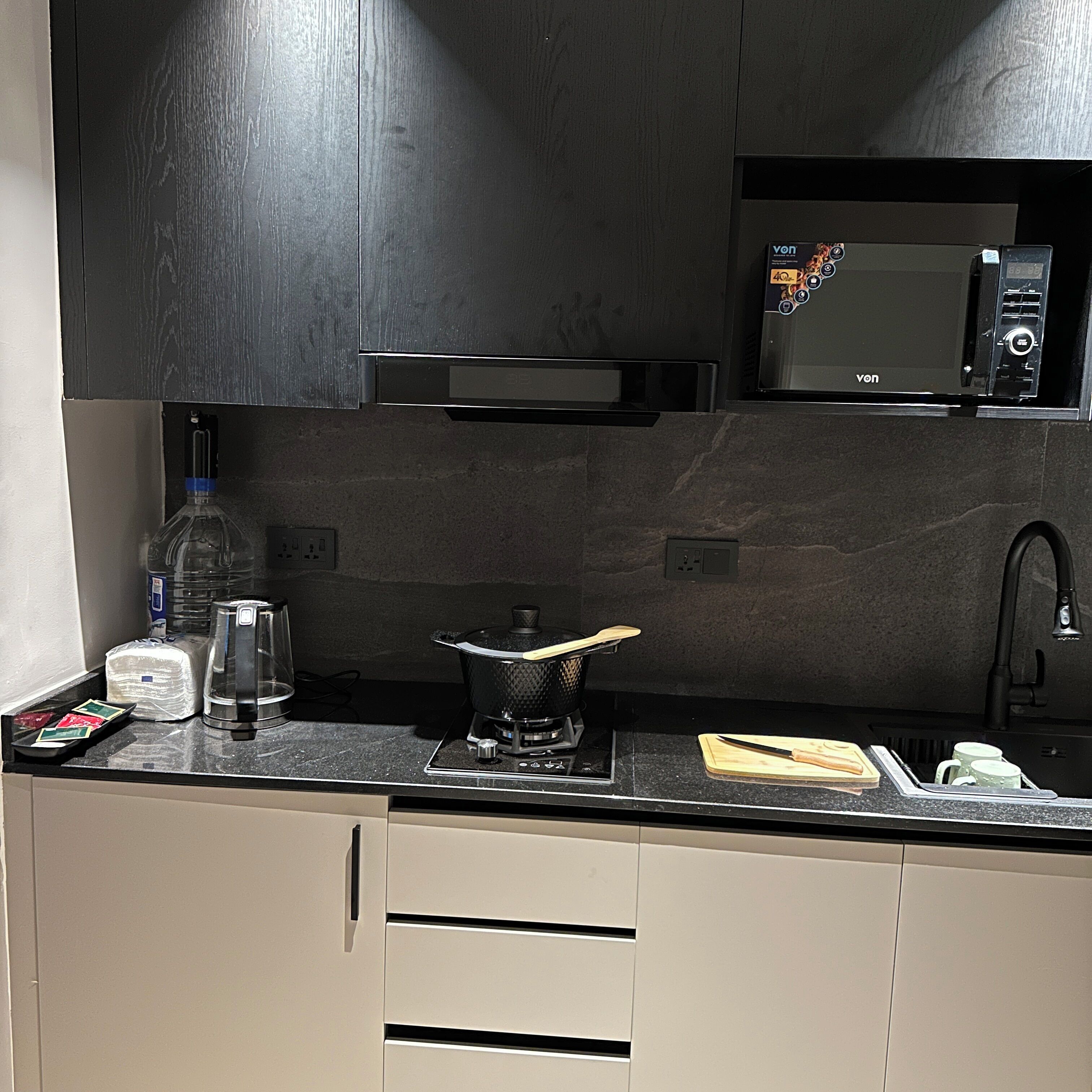 Een moderne keuken met een magnetron, waterkoker en fornuis.