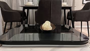 Una mesa de comedor con superficie de vidrio, rodeada por cuatro sillas.