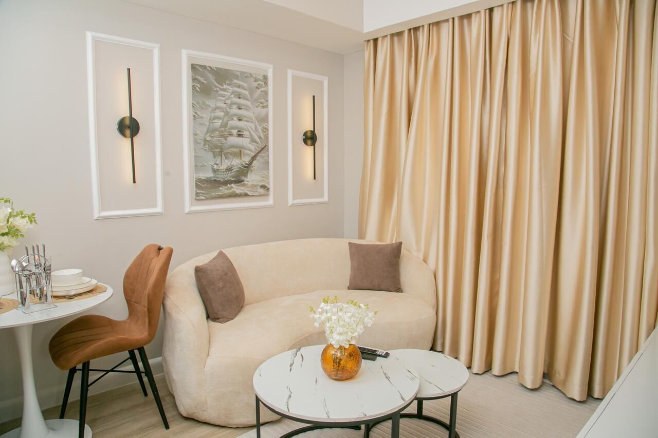 A modern living room with a sofa, a coffee table, a dining table with chairs, and artwork on the wall.