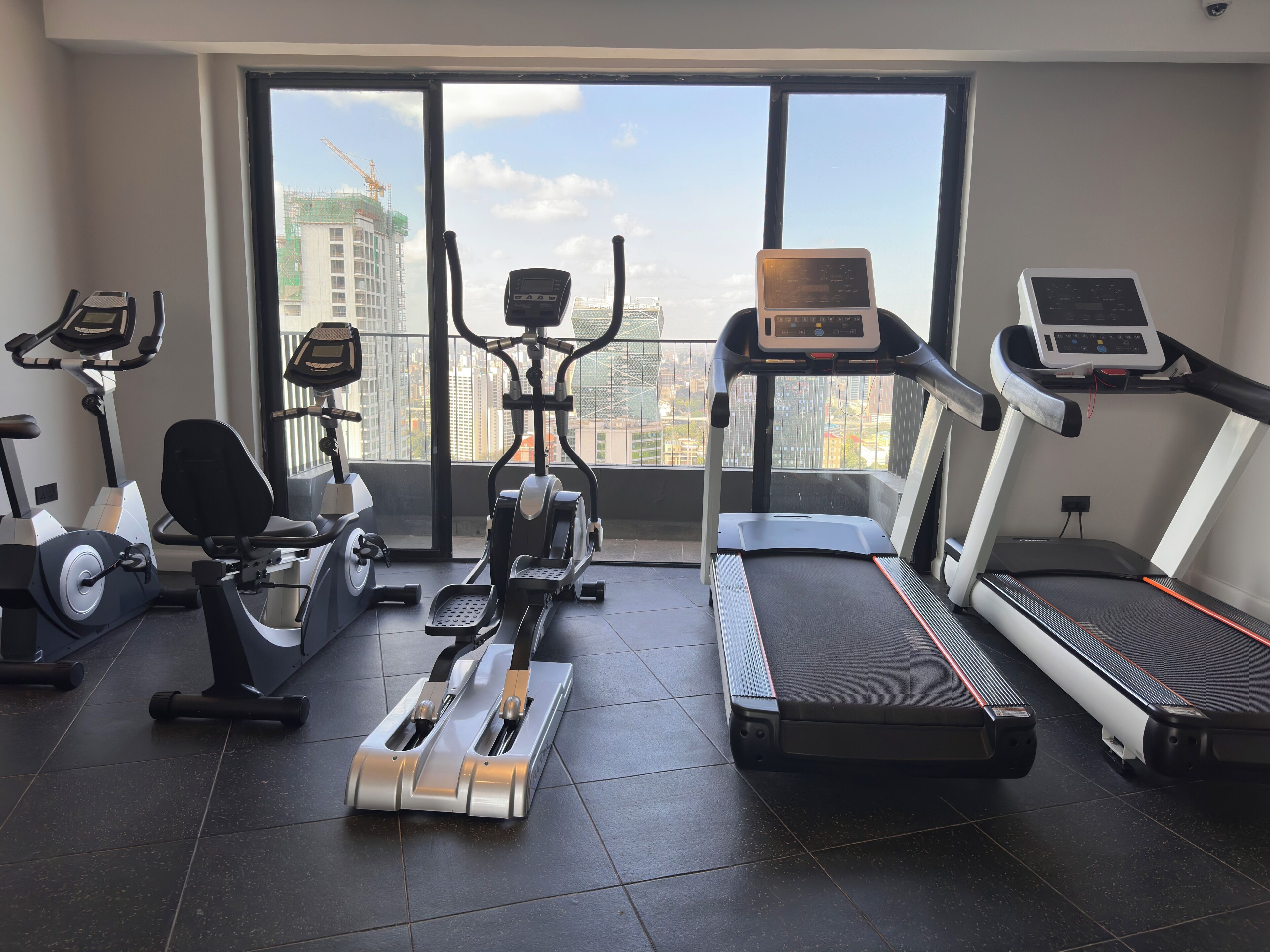 A gym with various exercise equipment, large windows, and a view of a construction site.