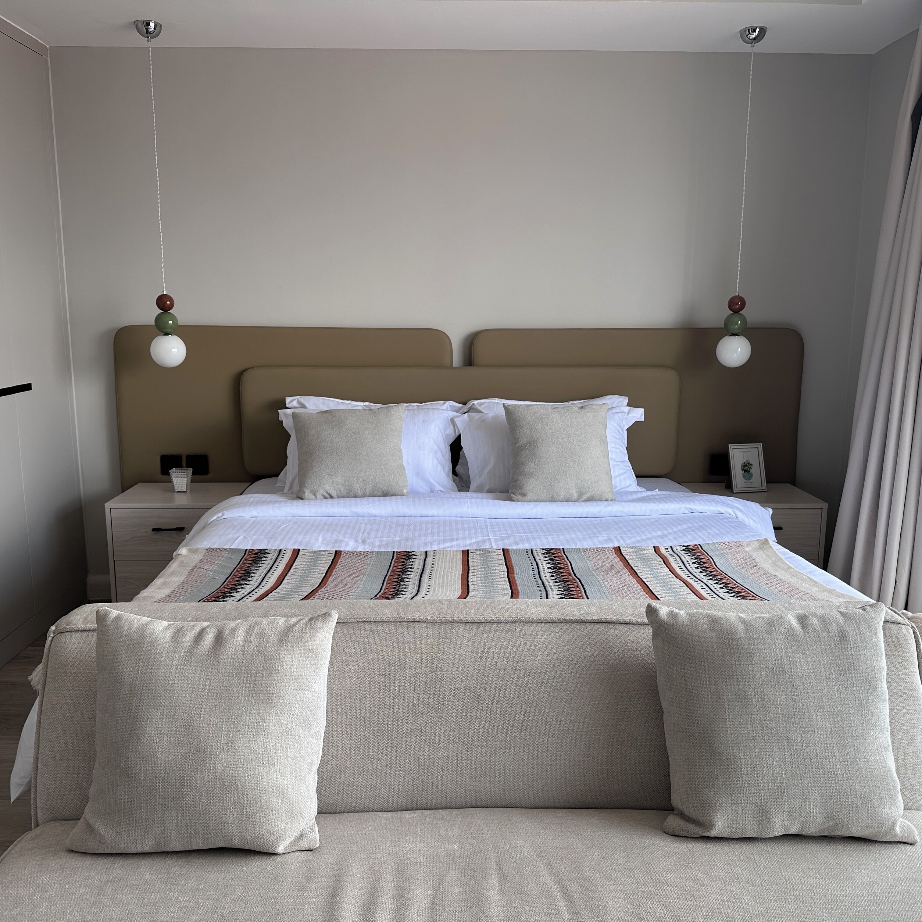 A modern bedroom with a large bed, two bedside tables, and a hanging light fixture.