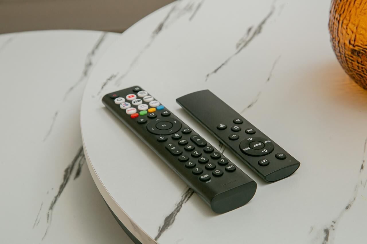 Two remote controls on a white marble table.