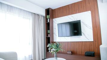 Ein modernes Wohnzimmer mit einem an einer Holzwand montierten Flachbildfernseher, einer Couch, einem Couchtisch und einer Vase mit Blumen.