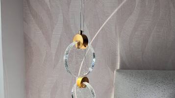 A wall with a herringbone pattern and a hanging light fixture with two circular glass elements and a gold-colored base.
