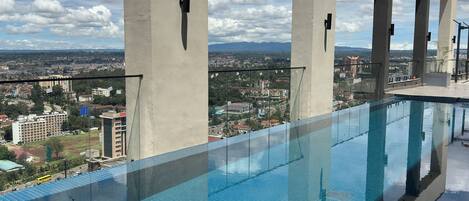 An infinity pool with a clear view of the cityscape and mountains in the background.