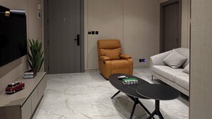 Een moderne woonkamer met een flatscreen-tv, een bank, een salontafel en een fauteuil.