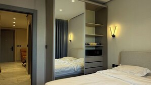 Een moderne hotelkamer met een groot bed, een inloopkast en een badkamer die door een open deur zichtbaar is.