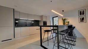 A modern kitchen with a central island, bar stools, and a pendant light. - Casa La Campanella by Villas Guide (Vodnjan)