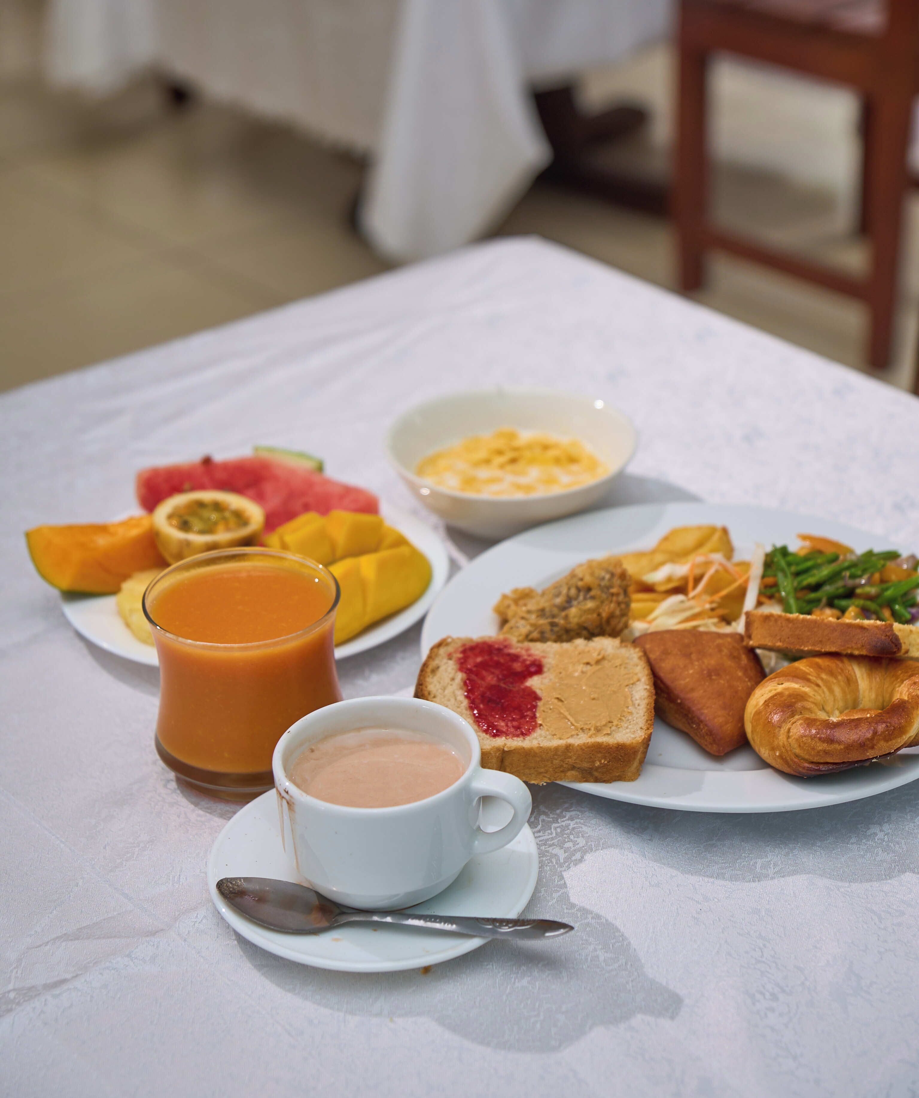 A breakfast table with a variety of food items including toast, pastries, fruit, and a cup of coffee.