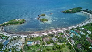 Vista aérea de un balneario costero con aguas cristalinas, una playa de arena y varias islas pequeñas.