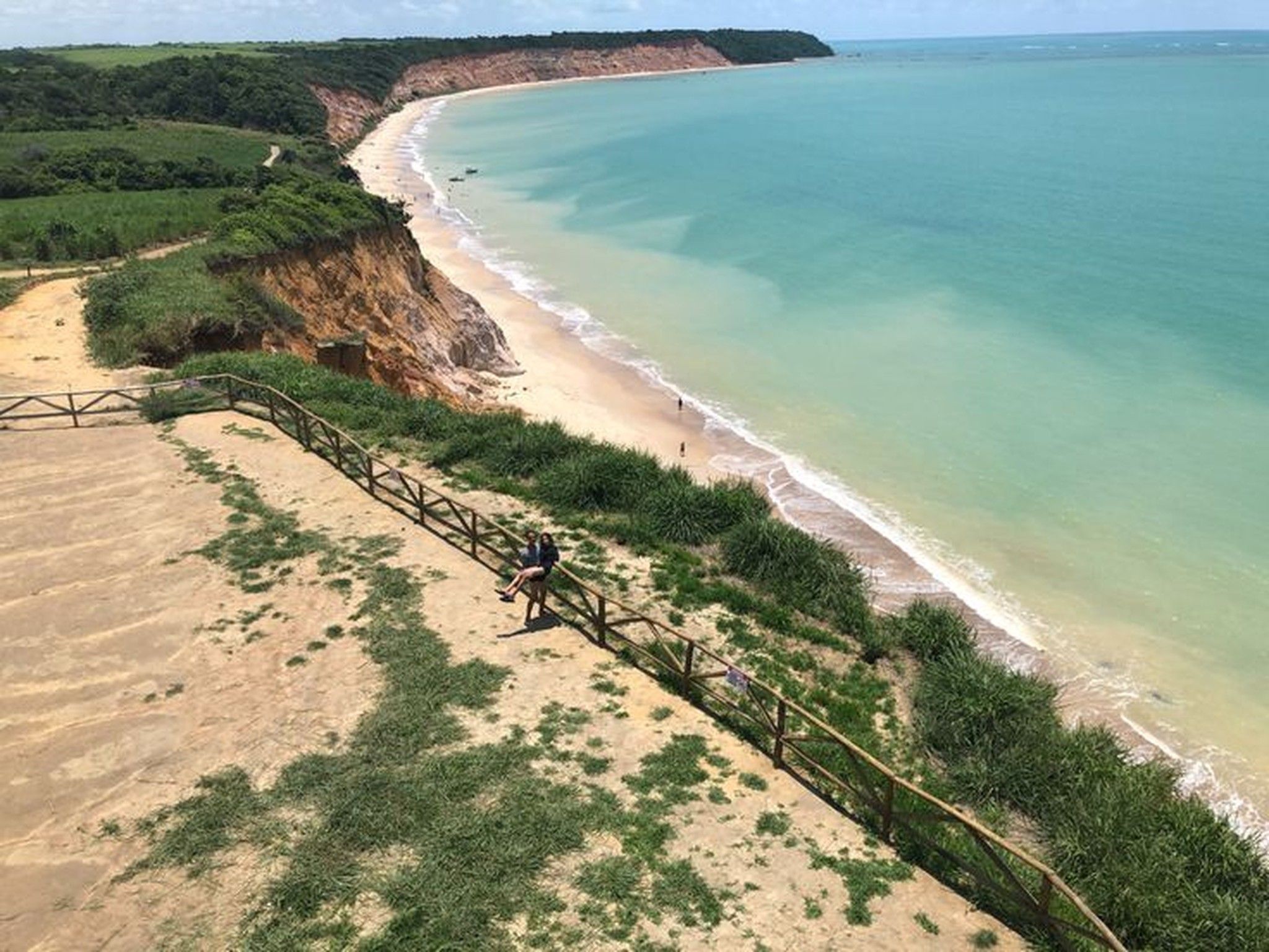 Eine Küstenlandschaft mit einem Sandstrand, einer Holztreppe, die zum Ufer führt, und freiem Blick auf den Ozean.