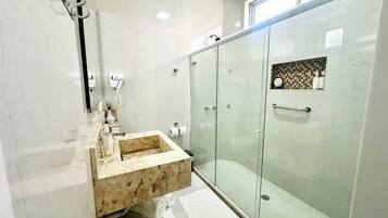 A modern bathroom with a marble sink, glass shower enclosure, and a towel rack.