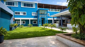 A modern building with a blue exterior, a well-maintained lawn, and potted plants.