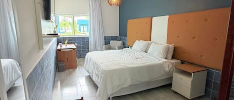 A modern bedroom with a bed, bedside table, and a small seating area.