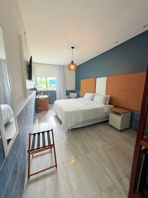 Un dormitorio moderno con cama, mesita de noche y una pequeña zona de estar.