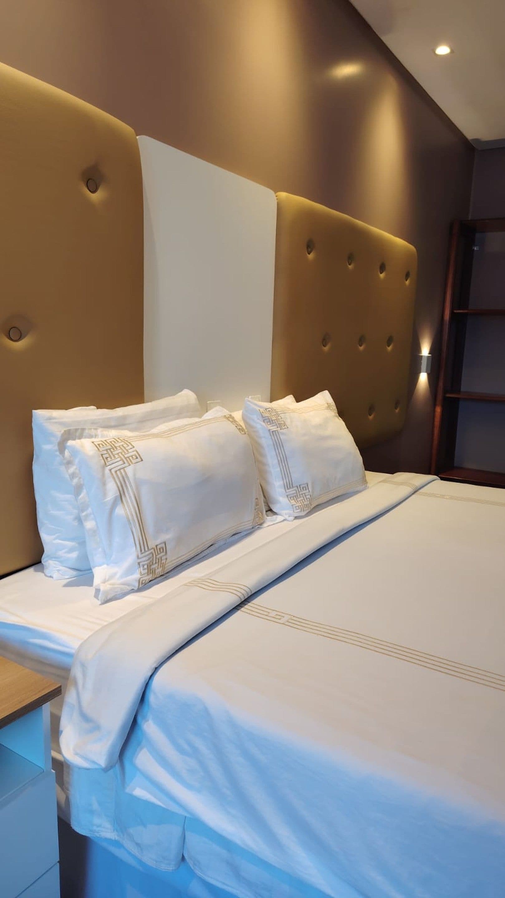 Una habitación de hotel con una cama grande, dos almohadas con estampado geométrico y un cabecero capitonado.