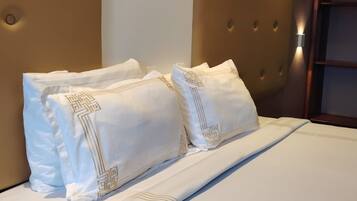 Una habitación de hotel con una cama grande, dos almohadas con estampado geométrico y un cabecero capitonado.