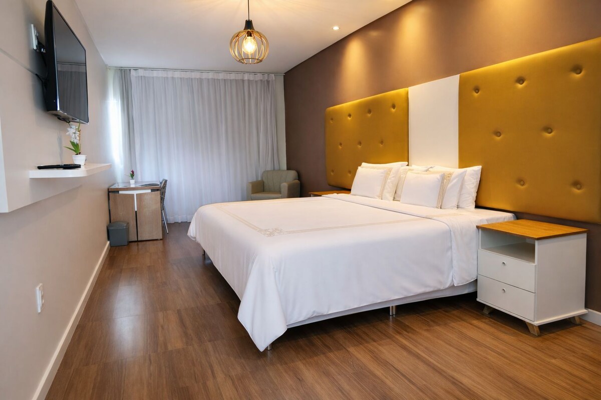Een moderne hotelkamer met een groot bed, nachtkastjes, een televisie en een klein bureau.