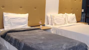 A hotel room with two beds, a large headboard, and a small table with a flower.